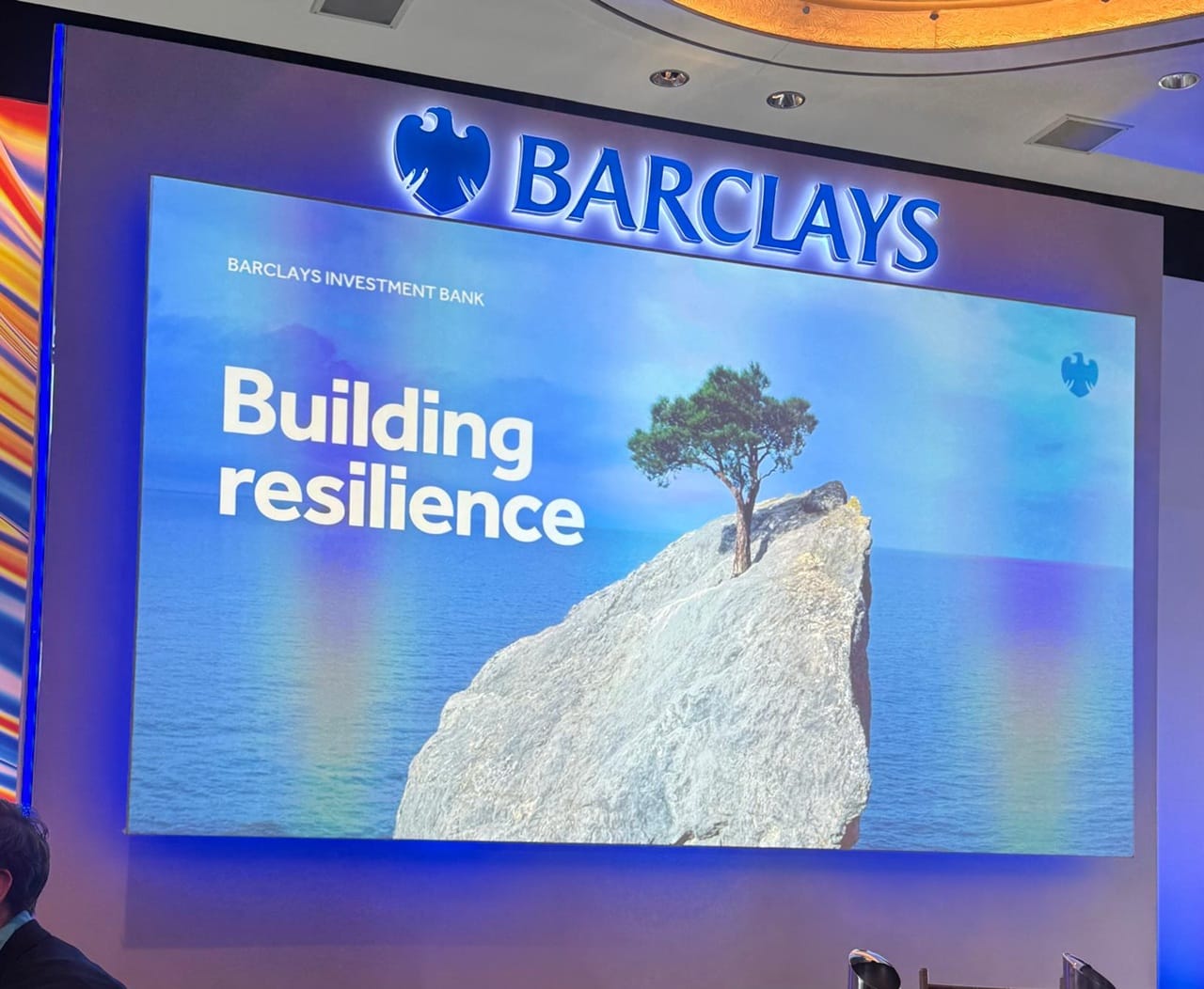 “Building resilience” keynote slide on stage at the Barclays NextGen Energy Conference 2026, with a Barclays Investment Bank backdrop and an image of a tree growing from a rock surrounded by sea