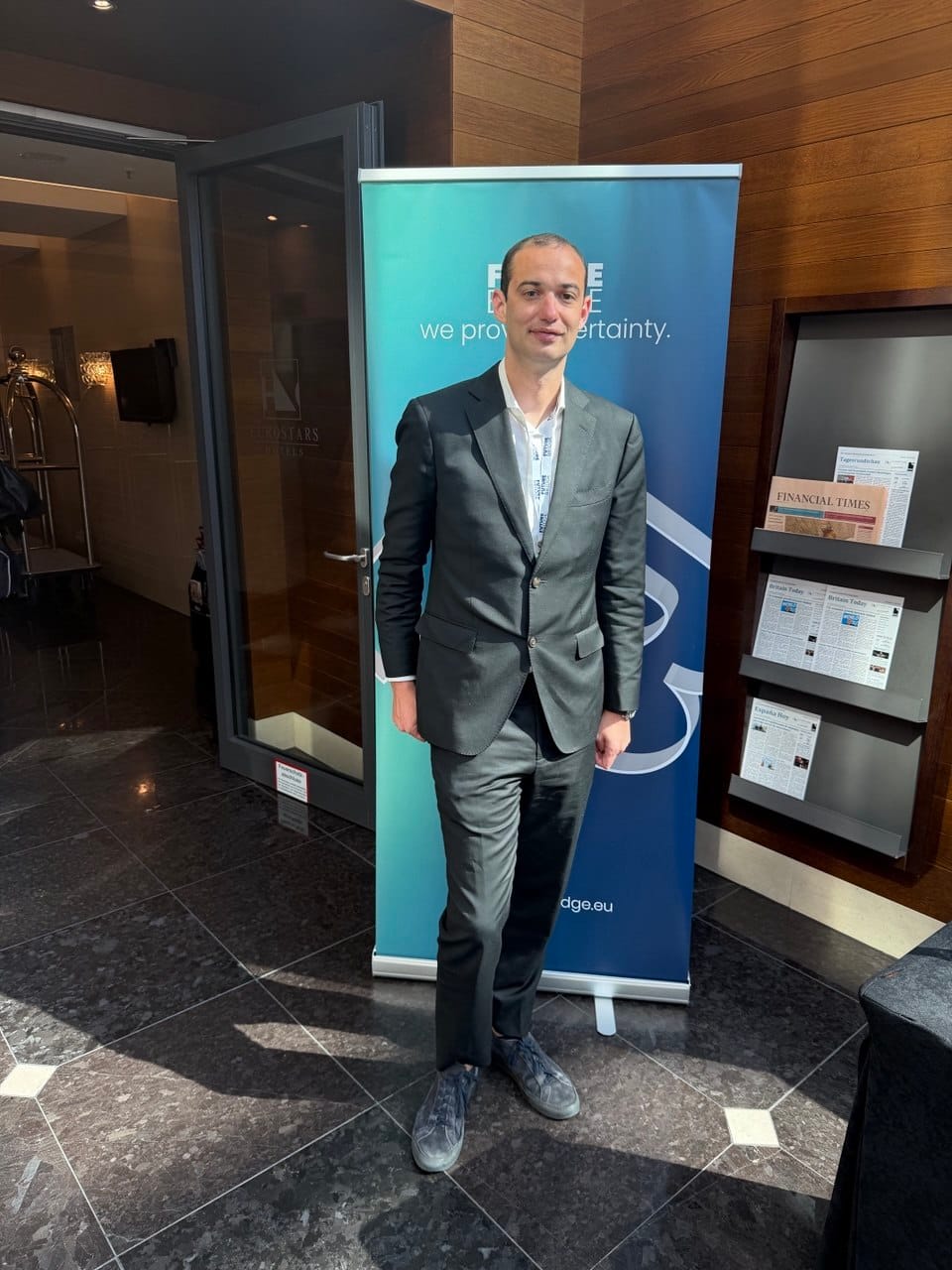 Ahmet Douas at the 4th Annual Scope 3 Summit venue in Berlin, standing in front of a Future Bridge banner at the Eurostars Hotel